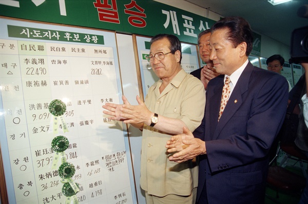 1995년 6월 28일 김종필 자민련 총재(왼쪽)가 서울 마포 당사 선거상황실에서 후보의 당선을 축하하는 꽃을 상황판에 달아주고 기뻐하며 박수를 보내고 있다. 오른쪽은 한영수 원내총무.