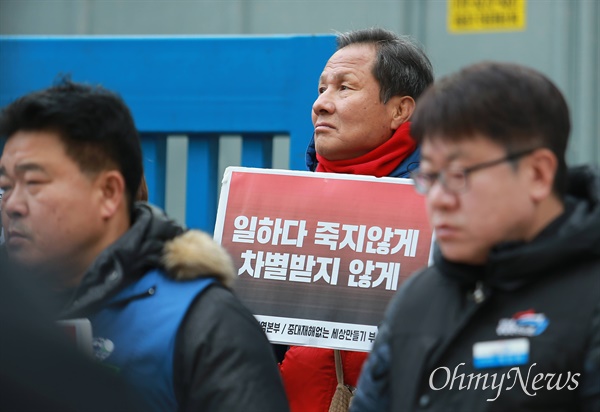 지난 1월 부산지방고용노동청 앞에서 열린 중대재해처벌법 관련 기자회견에서 한 노동자가 '일하지 죽지않게' 등이 적힌 손팻말을 들고 하늘을 쳐다보고 있다.