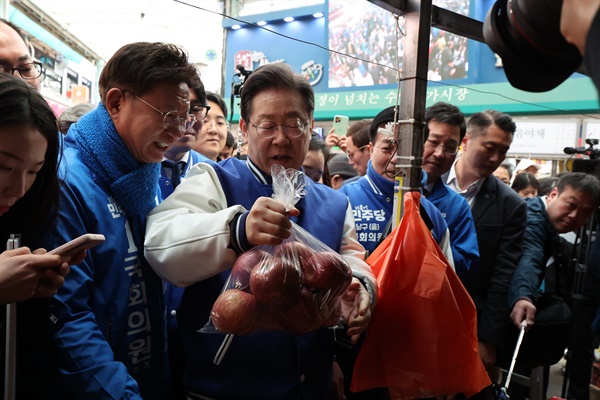15일 오전 울산 남구 수암시장을 방문한 이재명 더불어민주당 대표가 시장에서 사과를 구매하고 있다. 