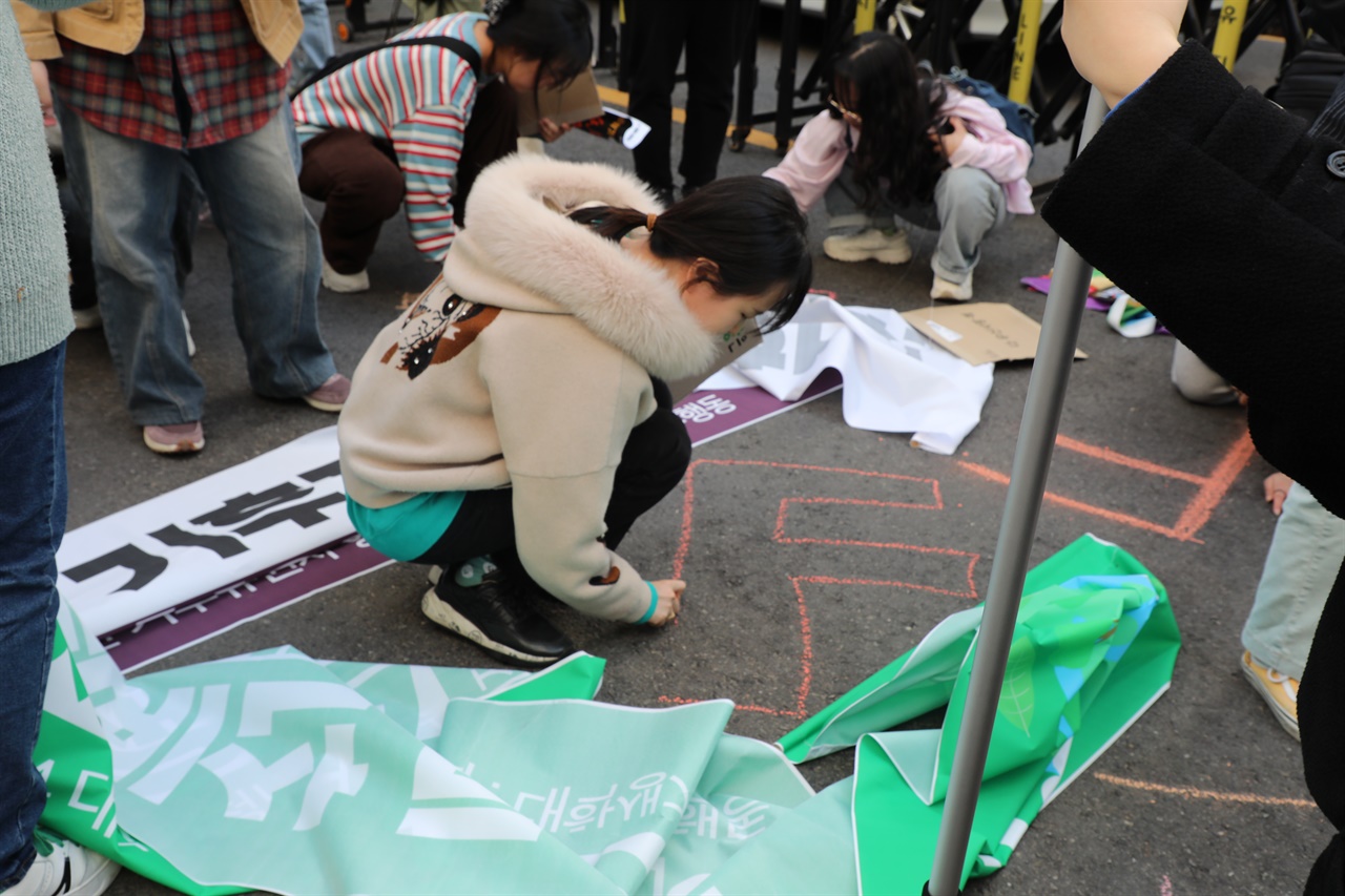 서울 여의도동 국민의힘 당사 앞에서 '2024 대학생·청년 기후유권자행동' 참여자들이 F학점을 뜻하는 'F'를 바닥에 그리고 있다