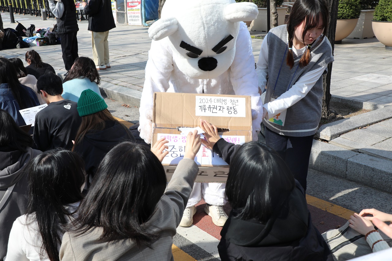 북극곰 분장을 하고 투표함을 들고 있는 한 활동가에게 집회 참여자들이 투표용지를 넣고 있다.