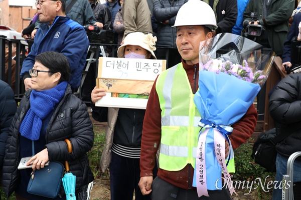 이재명 더불어민주당 대표가 25일 창원 반송시장을 방문했다. 한 건설노동자가 꽃다발을 들고 서 있다.