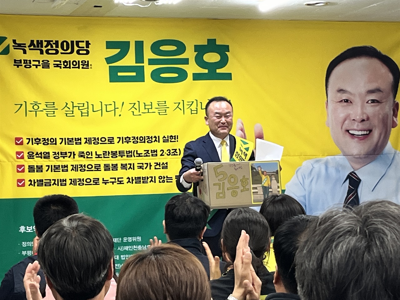 녹색정의당 김응호 인천 부평구을 국회의원 후보가 선거운동본부 출정식에서 지지자들의 선물을 받고 웃음 짓고 있다.