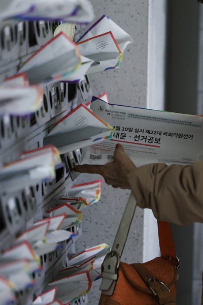 제22대 국회의원 선거를 열흘 앞둔 3월 31일 오전 서울 마포구 한 아파트 우편함에 꽂혀 있는 투표 안내문·선거 공보물을 주민이 가져가고 있다. 

