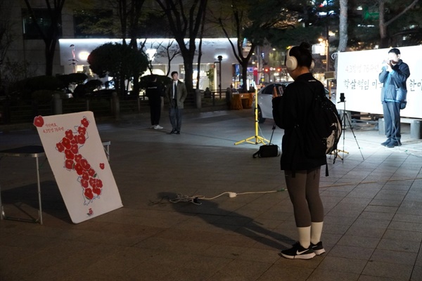 4.3항쟁 76주년을 맞이하는 2024년 4월 3일, 서울 보신각 앞에서 수요평화촛불이 개최되었다. 시민들의 참여로 한반도 모양에 4.3항쟁을 기억하는 동백꽃이 채워졌고 지나가던 시민이 사진촬영을 하고 있다. 