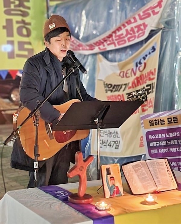 거리기도회에서 송기훈 목사가 기타를 치며 노래를 부르고 있다.