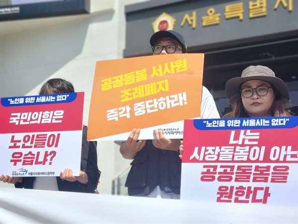 빈곤사회연대 정성철 활동가와 공공운수 서울 이현미 지부장은 노인을 위한 서울시는 없다" 규탄 기자회견에서 국민의힘을 비판하는 피켓을 들고 있다.
