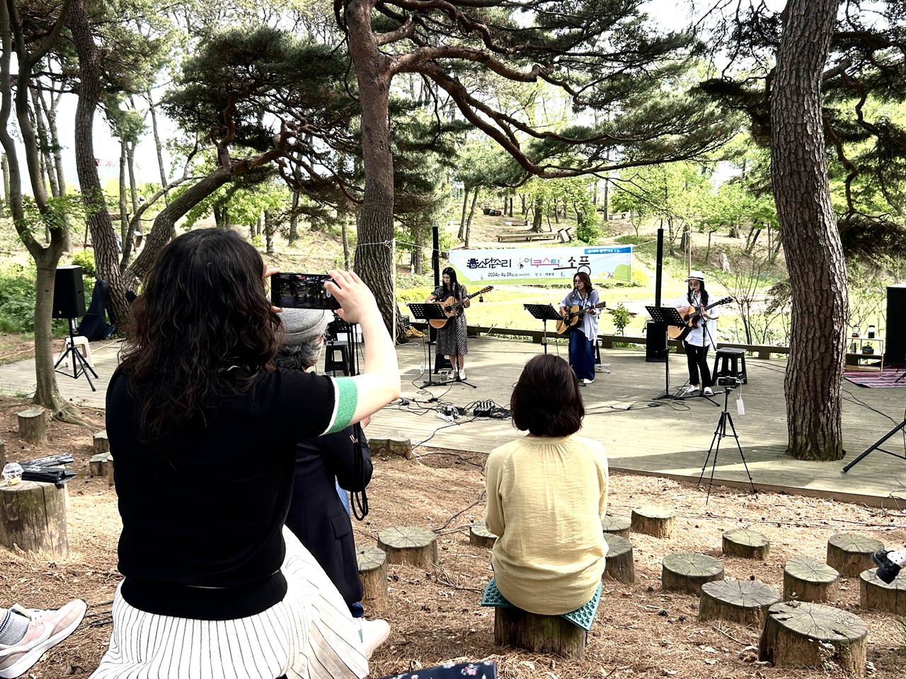 28일 오후 홍성지역 어쿠스틱 통기타 동아리 ‘소담소리’는 ‘봄 소풍’이라는 주제로 매봉재에서 숲속 음악회를 열었다. 한 관광객이 이들의 모습을 카메라에 담고 있다. 