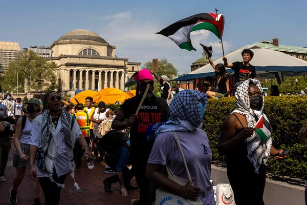 2024년 4월 29일 미국 뉴욕의 컬럼비아 대학교 캠퍼스의 시위대가 가자지구의 팔레스타인 사람들을 지원하기 위해 설치된 야영지 주변에서 피켓을 들고 있다.