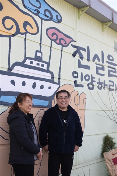 4.16세월호참사가족협의회 사무실 공간 한편 '진실을 인양하라'는 벽화 앞에서 사진을 촬영하던 유영민·김동녀씨 부부가 오랜만에 만난 4.16 가족들을 보며 환하게 웃고 있다.
