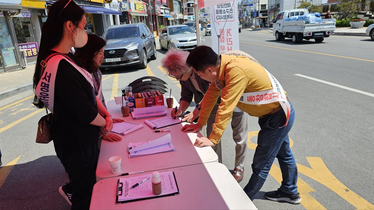 행인인 군민이 추진위원의 안내에 따라 미래항공 연구개발센터 태안군 유치를 위한 서명에 동참하고 있다.