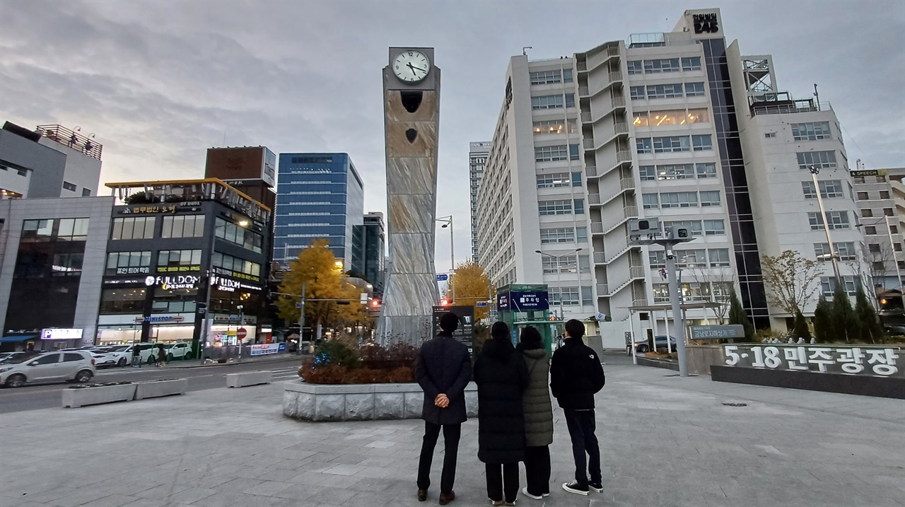 광주를 찾은 한 가족이 민주광장 시계탑 앞에서 1980년 5월 그날을 회상하고 있다. 시계탑에선 5시 18분, 노래 '임을 위한 행진곡'이 흘러나오고 있다.
