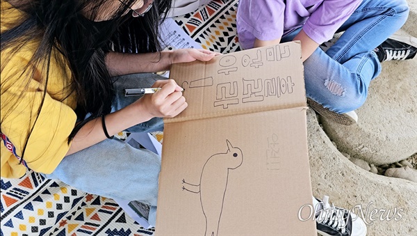세종보 농성장 앞에서 예배를 마친 아이가 박스 종이에 흰목물떼새를 그려넣었다.