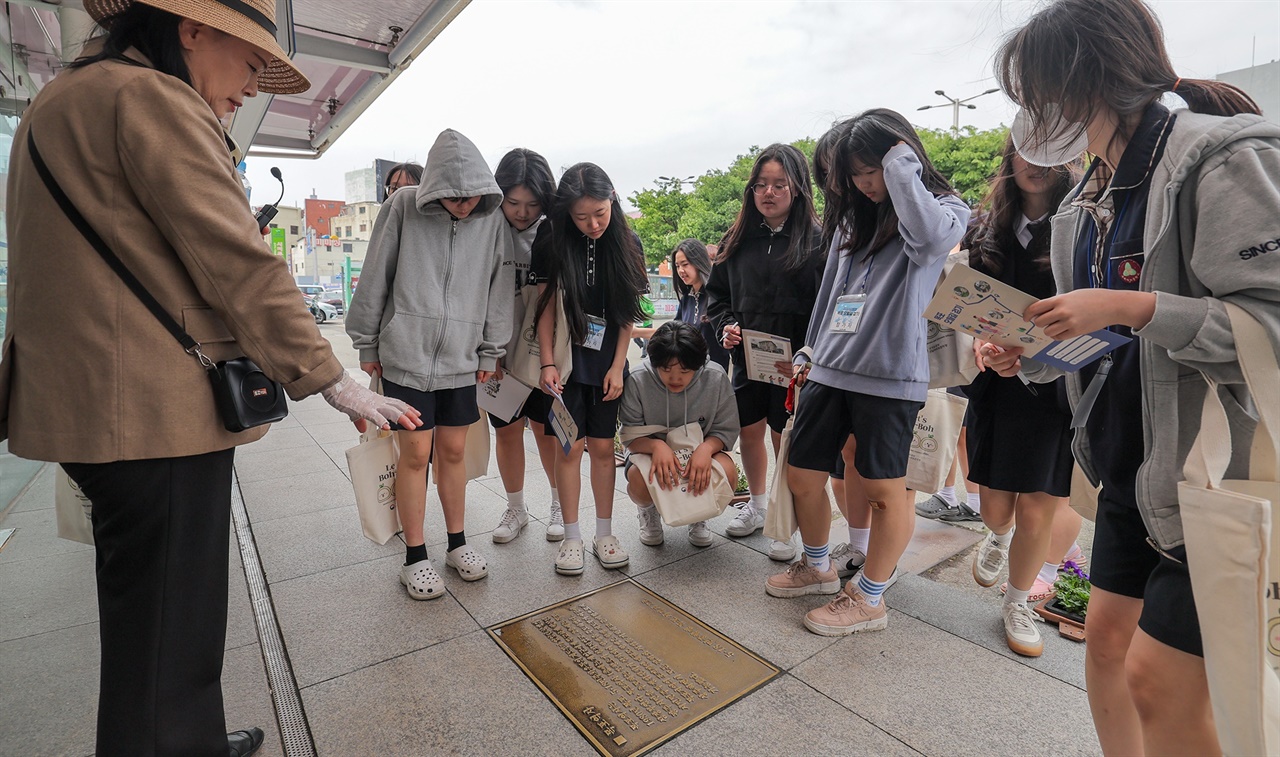 5월 7일 '목포 오월길' 걷기에 참가한 목포여중 학생들이 해설사의 설명을 들으며 목포역광장에 새겨진 표지석을 보고 있다.