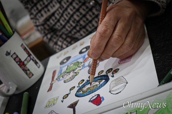 임영희 작가가 지난 15일 전남 화순 수만리 자택에서 자신이 늘 작업하던 탁상에 앉아 색연필로 그림을 덧칠하고 있다. 2011년 뇌졸중으로 오른손을 못 쓰게 된 그는 왼손으로 그림을 그린다.