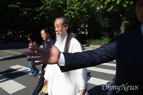 역술인 천공(본명 이천공)이 21일 오후 서울 광화문역 구내 한 도자기 전시장을 방문한 뒤 나오고 있다. 한 수행원이 촬영을 제지하며 손으로 가리고 있다.