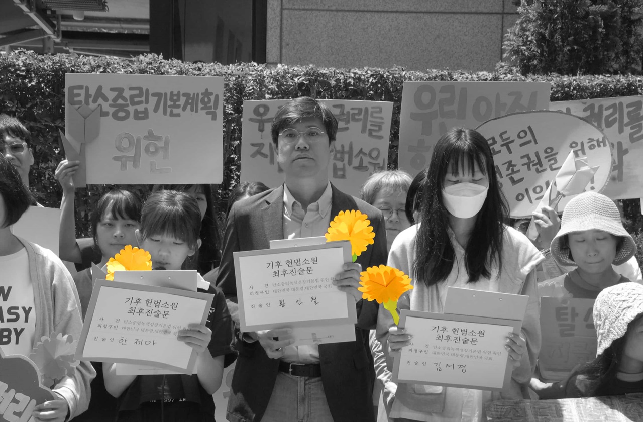 기후헌법소원 마지막 공개변론이 열린 지난 21일 서울 종로구 헌법재판소 앞에서 청구인들이 ‘반드시 행복은 오고야 만다’란 뜻을 가진 노란색 마리골드 종이꽃을 들고 위헌 결정을 촉구하는 기자회견을 하고 있다.