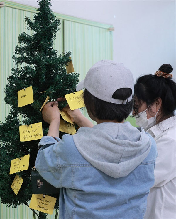 추모 메시지를 나무 모형에 매달고 있는 참석자들