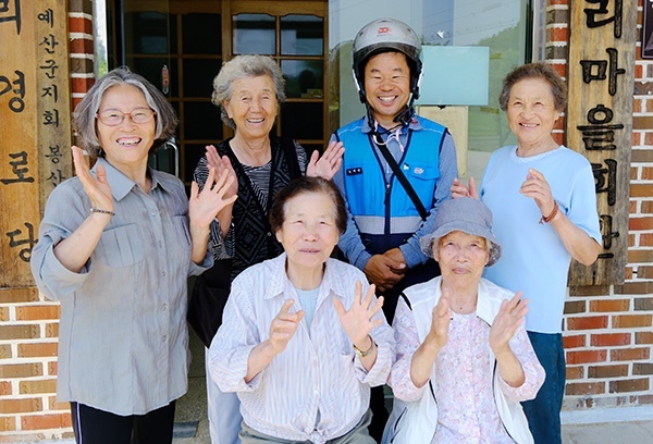 김재천 집배원이 마을 어르신들과 사진을 찍고 있다.