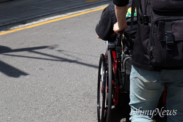 지난 6월 27일 서울 종로구 혜화역 인근 거리에서 정창조 노들장애학궁리소 연구활동가가 박경석 전장연 상임공동대표의 휠체어를 밀며 함께 이동하고 있다.