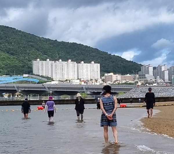  사람들이 웅천해수욕장의 바다를 맨발로 걷고 있다.