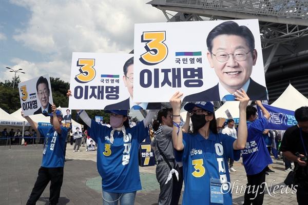  이재명 더불어민주당 당대표 후보 운동원들이 18일 더불어민주당 제1차 정기전국당원대회가 열리는 서울 송파구 올림픽체조경기장(KSPO-DOME) 입구에서 지지를 호소하고 있다.  