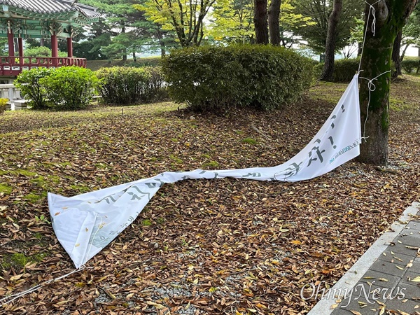  23일 독립기념관 정문 앞 1km 구간에 설치됐었던 '김형석 독립기념관장 아웃' 현수막들이 끈이 풀린 상태로 바닥에 떨어져 있다. <오마이뉴스> 확인 결과, 천안 동남구청이 현수막 10개를 철거했다. 