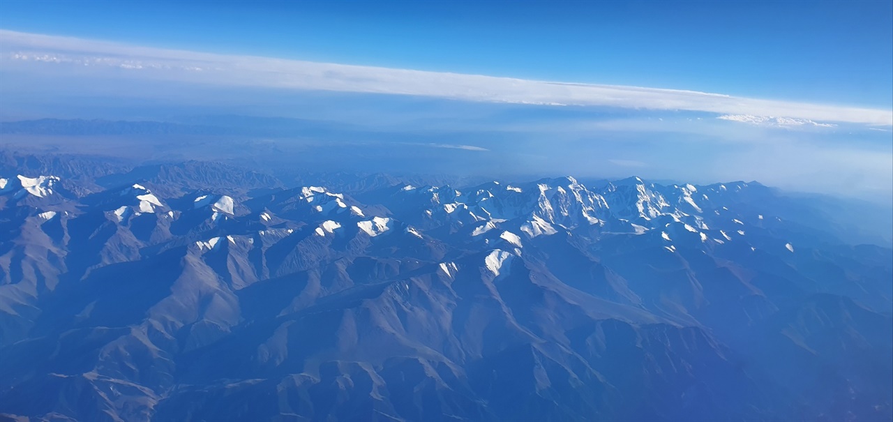 하늘에서 바라본 천산산맥 알마티에 가까워오자 창 너머로 고산 영봉과 만년설이 물결치듯 다가왔다.