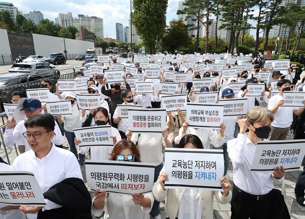  의대교수들이 3일 오후 서울 용산구 대통령실 인근에서 열린 한국의학교육평가원 무력화 저지 결의대회에서 손팻말을 들고 구호를 외치고 있다.