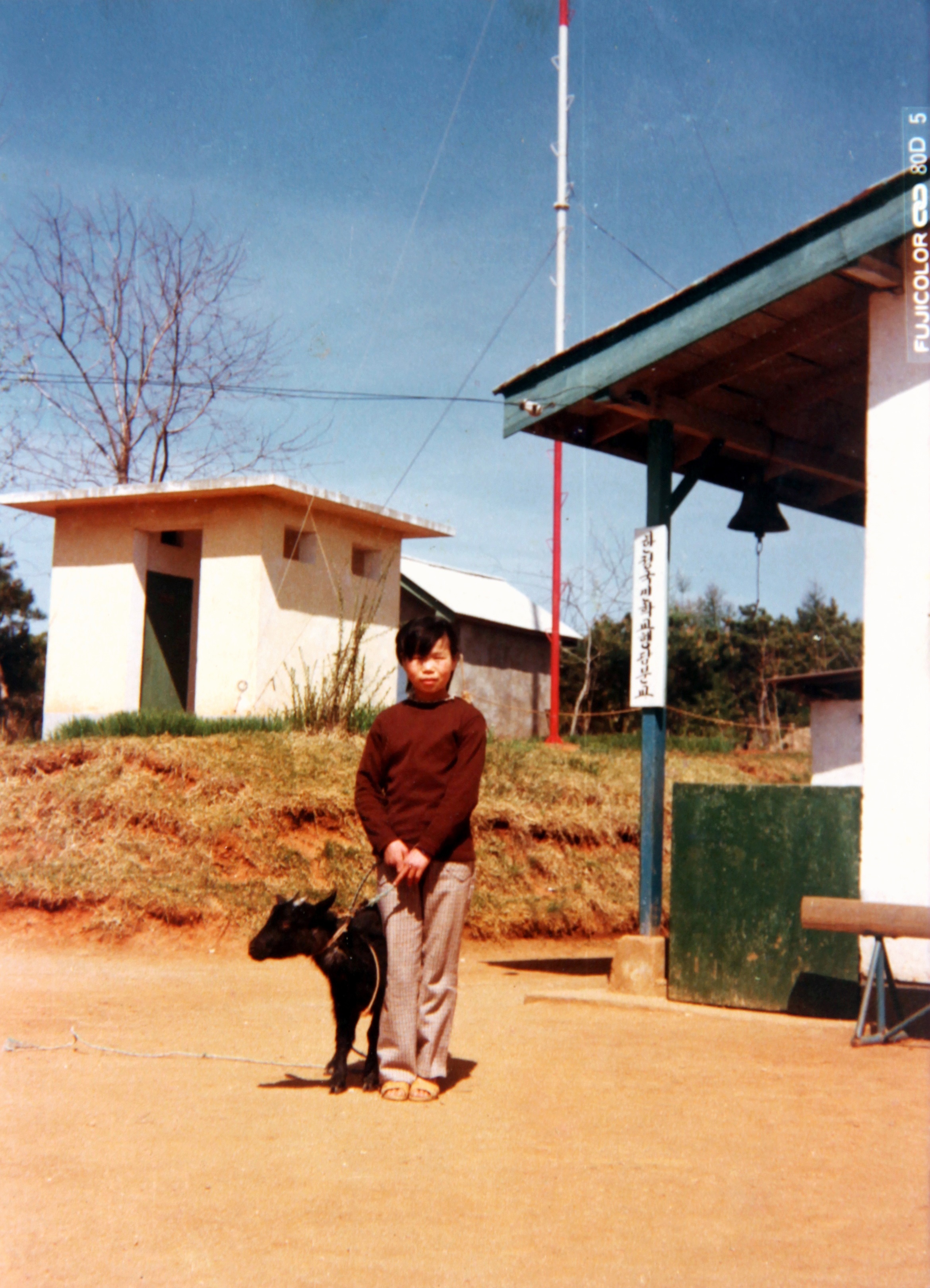  행담분교에서 염소와 함께. 뒤로 '한정국민학교 행담분교'라는 푯말이 보인다.