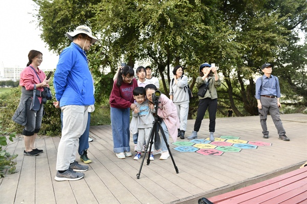  수리부엉이를 멀리서 필드스코프로 관찰하고 있다. 그 모습을 보고 모두들 신기한 듯 감탄한다.