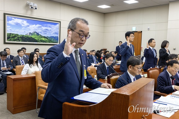  정인섭 한화오션 거제사업장 사장이 15일 오후 서울 여의도 국회에서 열린 환경노동위원회의 경제사회노동위원회, 중앙노동위원회, 최저임금위원회 등에 대한 국정감사에서 선서하고 있다. 정 사장 뒤로 뉴진스의 멤버 하니가 참고인 자격으로 출석해 있다.