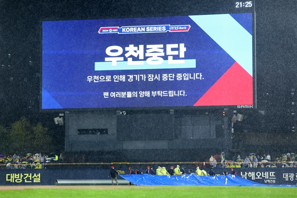   21일 광주 기아챔피언스필드에서 열린 2024 신한 SOL뱅크 KBO 포스트시즌 한국시리즈 1차전 삼성 라이온즈와 KIA 타이거즈의 경기. 6회초 강한 비로 경기가 잠시 중단되자 경기장 관계자들이 방수포를 경기장에 덮고 있다. 2024.10.21