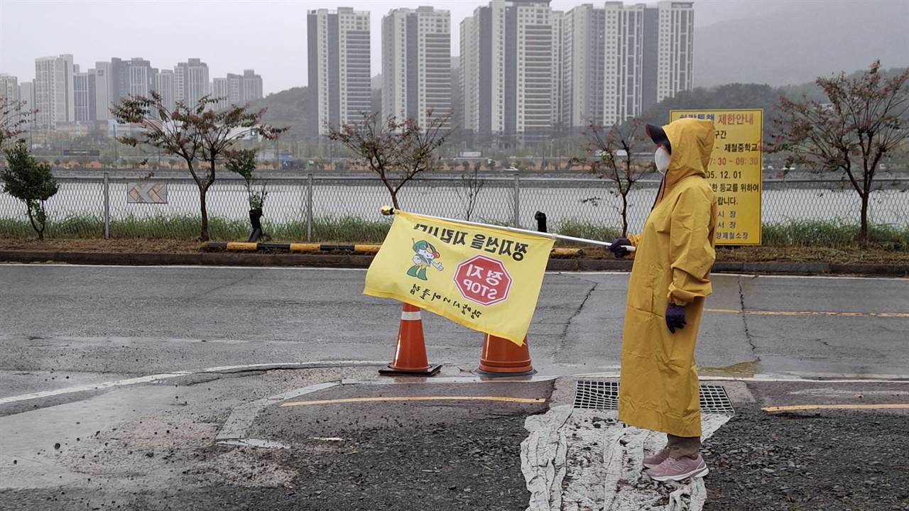 우천시 시니어클럽 회원 근무 중 비오는 날 비옷을 입고 시니어클럽 회원이 교차로에서 근무하는 모습.