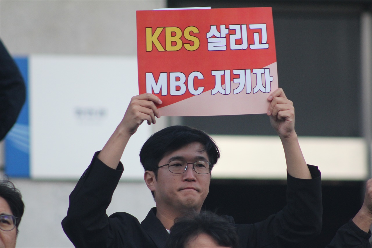 각계 원로와 언론단체 ‘위법한 KBS 사장 선임 중단 촉구' 23일 오전 9시, 각계 원로와 언론단체가 KBS 본관 앞에서 ‘위법한 KBS 사장 선임 중단 촉구’ 기자회견을 열었다. 한 참가자가 피켓을 들고 있다.