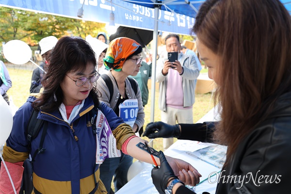  지난 27일 대구 동구 봉무동 단산유적공원에서 열린 제9회 통일염원 걷기대회에 참가한 한 참가자가 팔에 타투를 하고 있다.