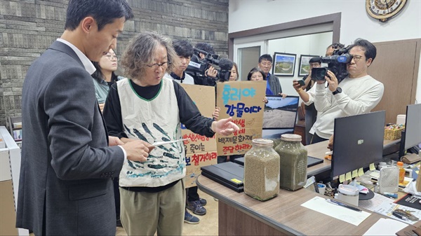  문성호 보철거시민행동 공동대표가 고마나루에서 퍼온 펄과 모래를 공주시장실에 전달하고 있다.  