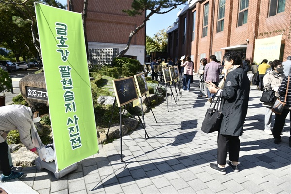  고산성당 마당에서 열린 팔현습지 사진전의 사진들을 둘러보고 있는 고산성당 신자들