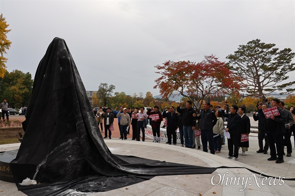  영남대 민주동문회 회원들이 10일 오후 천마아너스파크에 세워진 박정희 동상을 검은 천으로 두른 후 '임을 위한 행진곡'을 부르고 있다.