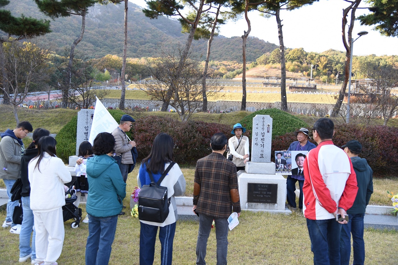  2코스 참가자들이 장군2묘역에 안장된 김진기의 묘 앞에서 정성일 해설사의 이야기를 듣고 있다.