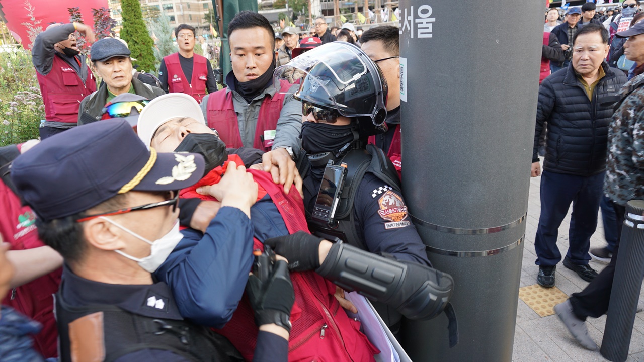  부상자를 쫓아가 끌고 가려 하는 경찰에 항의하는 참가자의 목덜미를 또다른 경찰이 잡아 당겨 숨이 막히게 했다.