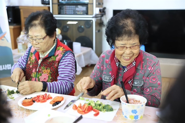 용두2리 마을회관에서 '찾아가는 요리교실'에 ？참여했다. 함께 참여한 어르신들도 요리교실에서 밝은 미소로 즐거운 시간을 보내고 있다. 요리하는 손길마다 호기심과 흥미가 느껴지며, 서로에게 조언을 건네고 도움을 주며 웃음을 나누는 모습이 훈훈하게 담겼다