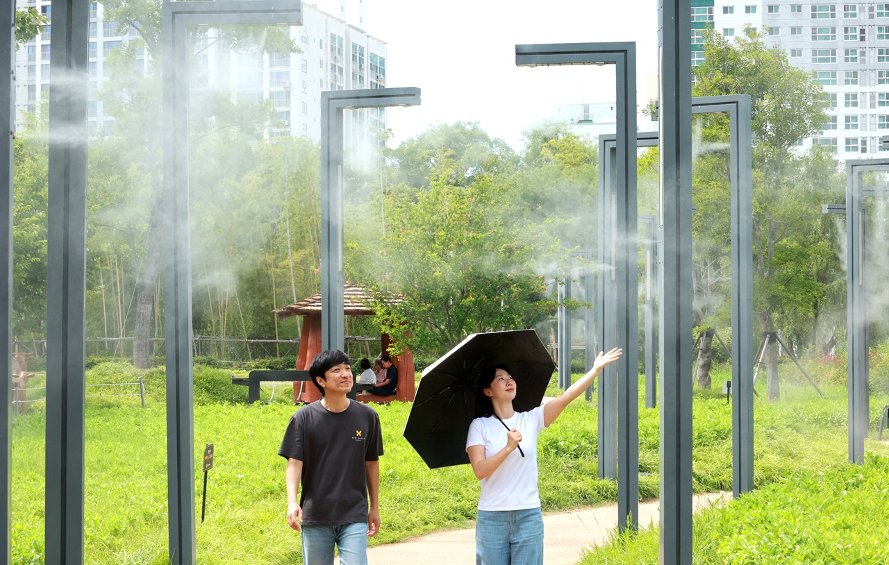   6월부터 본격 가동에 들어간 부산시민공원 쿨링포그(Cooling Fog) 시설에서 17일 시민들이 물안개가 뿜어져 나오는 산책로를 걸으며 더위를 식히고 있다. 2026.6.17