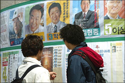 17대 총선 서울의 한 부재자 투표소에서 선거벽보를 살펴보고 있는 대학생들.(자료사진)