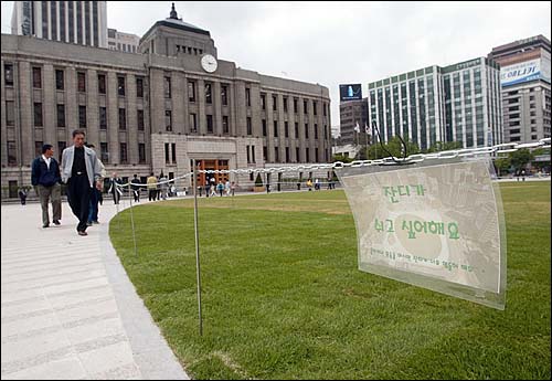 지난 2004년 5월 서울광장의 모습. 잔디가 훼손되면서 새 잔디를 심은 구역에 '진디가 쉬고 싶어해요'라는 안내문이 내걸려 일반인들의 출입이 통제되고 있다.