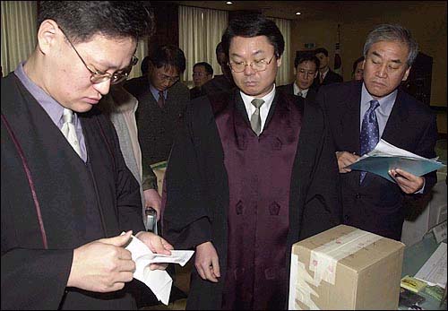 지난 2003년 1월 27일 서울 마포 소재 서울지법 서부지원 10층에서 은평구 유권자들의 재검표가 실시되고 있다. 법복을 입은 법관이 투표용지를 확인하고 있는 모습을 이 지역출신 한나라당 이재오 의원(오른쪽)이 지켜보고 있다. 