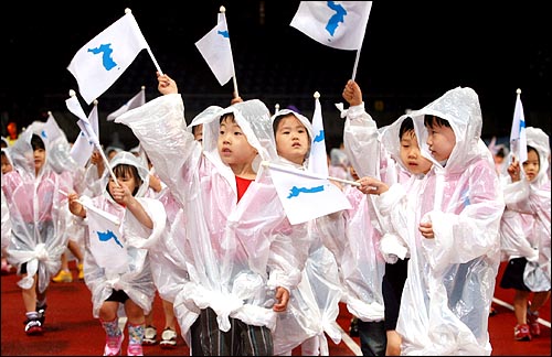 2006년 6월 14일 장대비가 쏟아지는 가운데 전남 광주 월드컵경기장에서 열린 6·15 남북공동선언 6돌 기념 민족통일대축전 개막식에서 어린이환영단이 한반도기를 흔들며 입장하고 있다.
